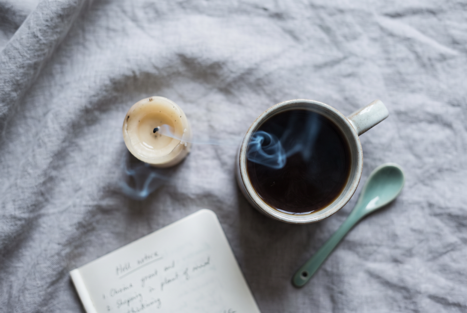 Flat lay of a burnt-down candle, a full mug of tea gone cold, and an unchecked to-do list
