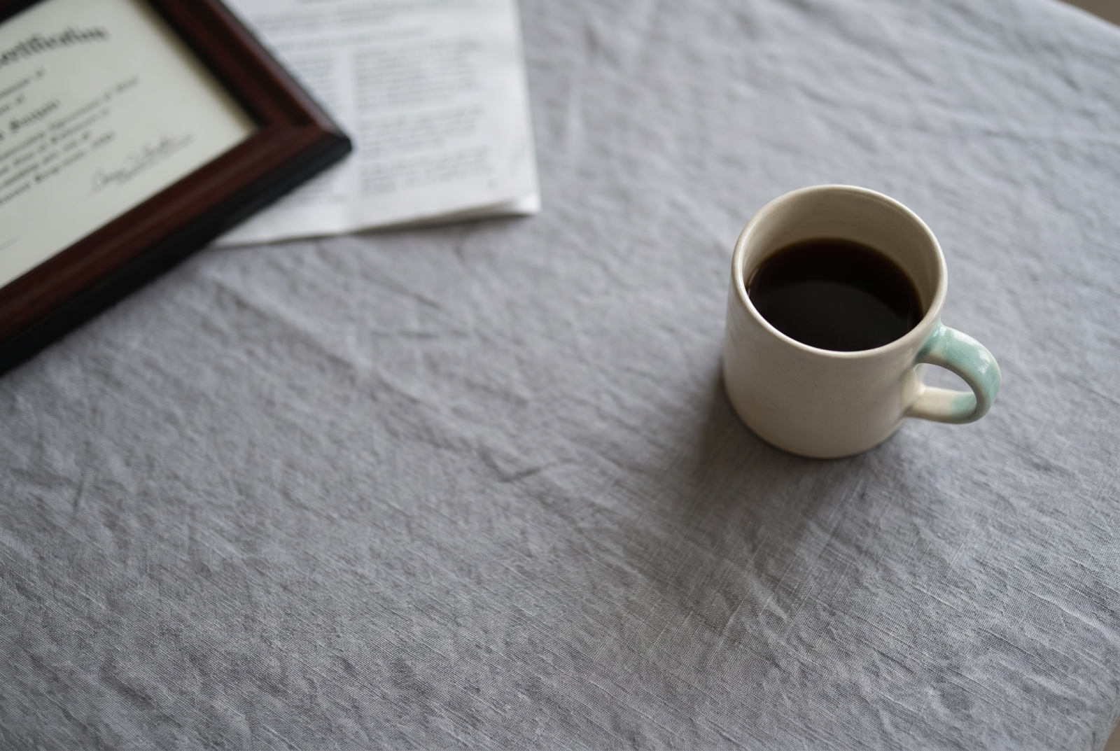 Flat lay of a resume and certificate softly blurred and set aside beside a plain coffee cup, framed to feel dismissed rather than celebrated