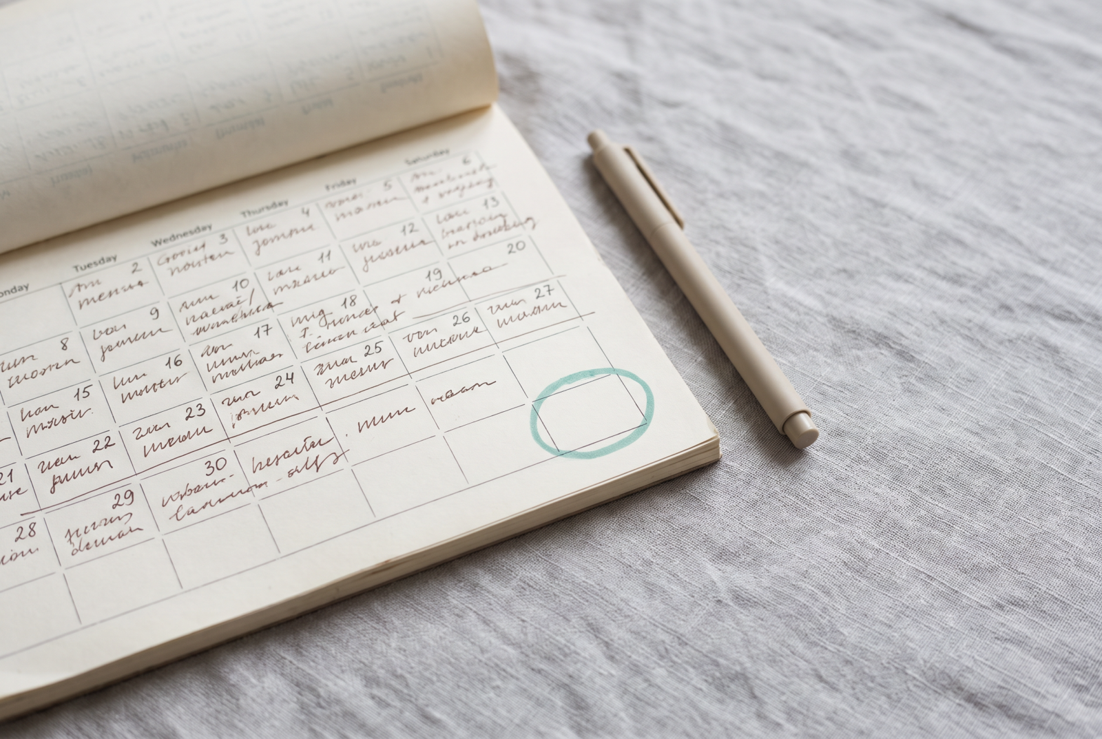 Flat lay of a calendar page completely filled with other people's commitments, with one small empty square circled in green